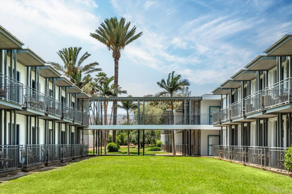 The courtyard breathes through its palms.