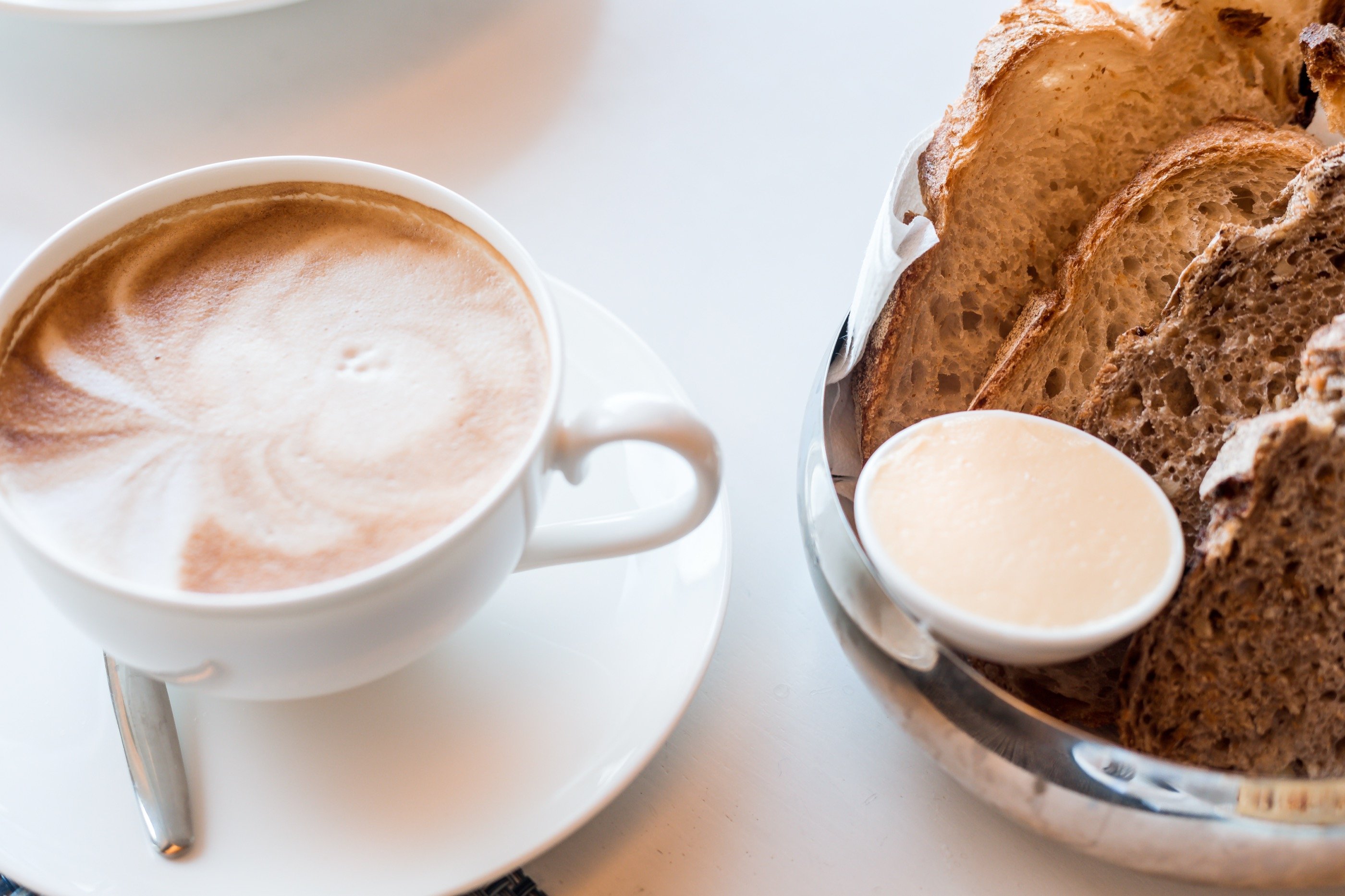 Morning — coffee, bread, white marble.