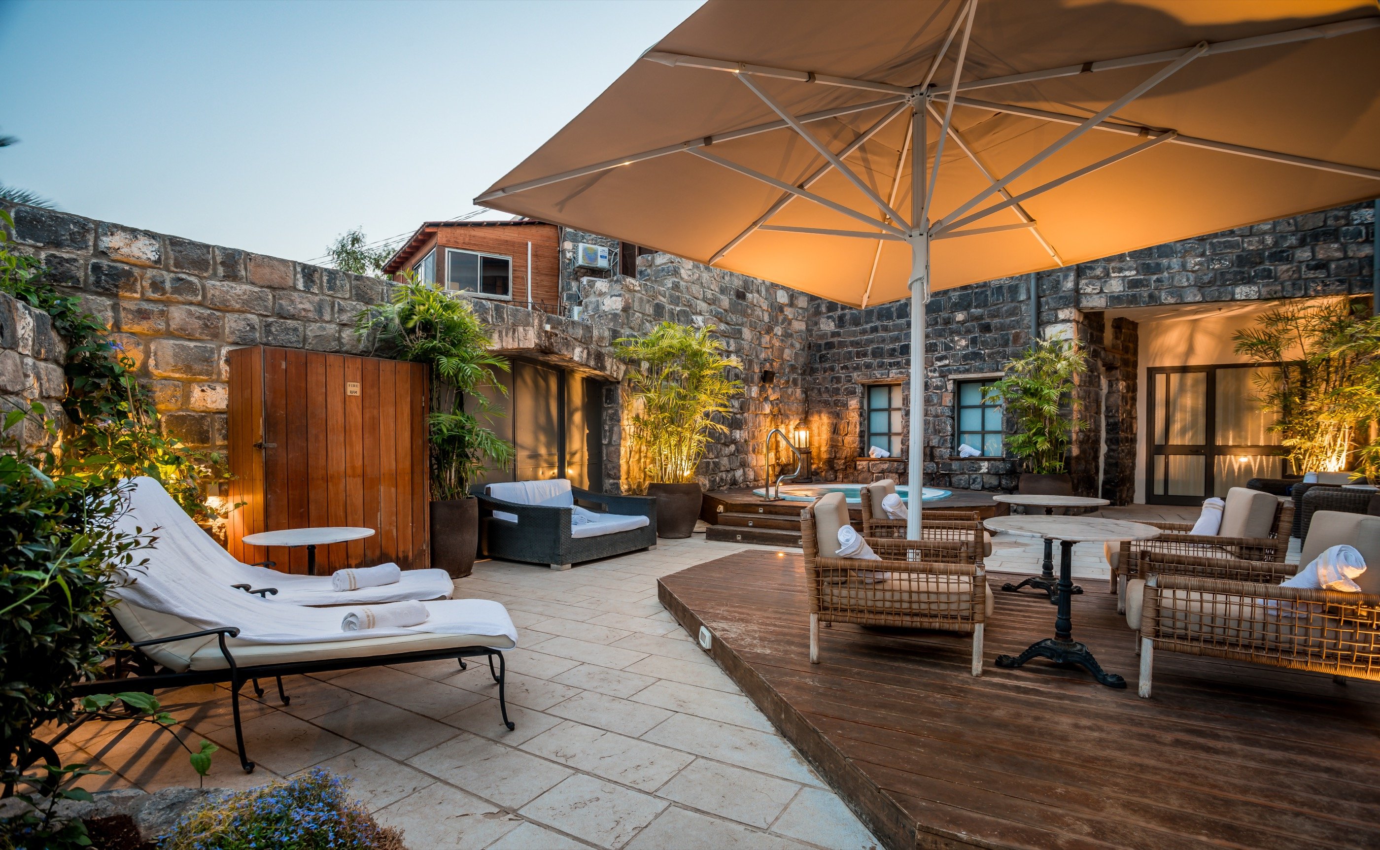 The courtyard at dusk — daybeds under a single umbrella.